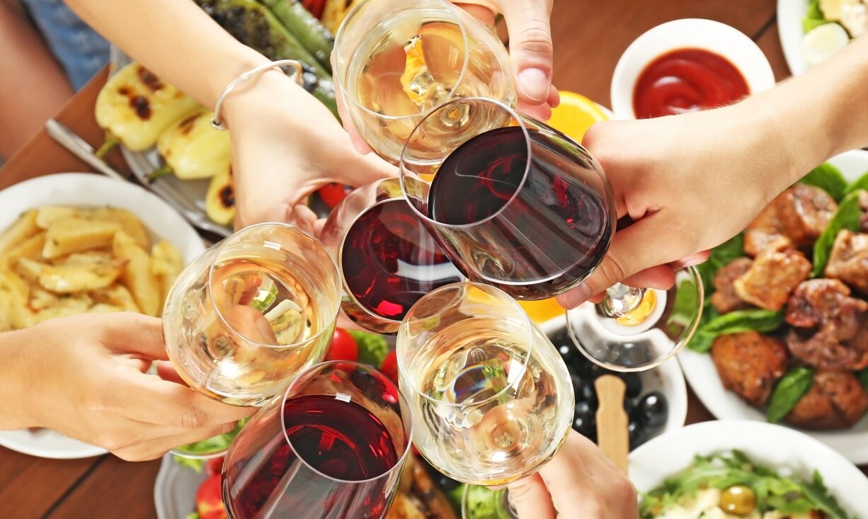 Anstoßen mit Rot- und Weißwein über einem reich gedeckten Tisch