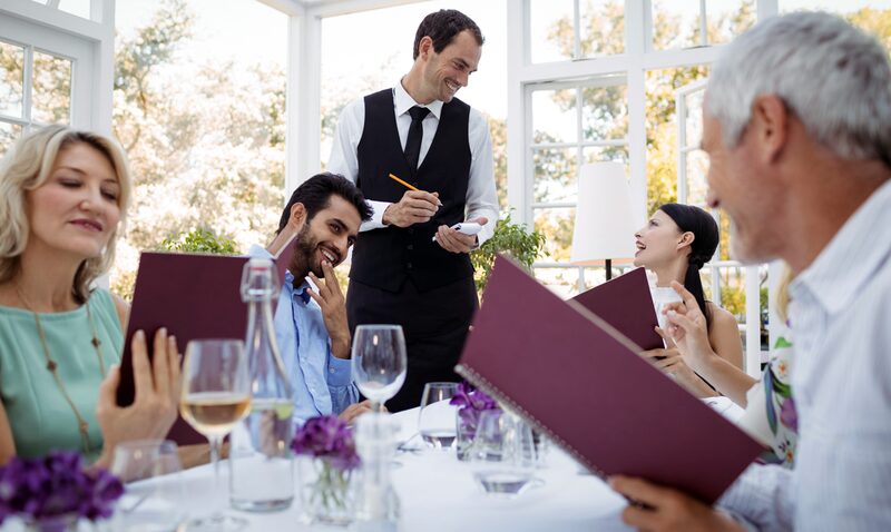 Gäste studieren die Weinkarte am Restauranttisch
